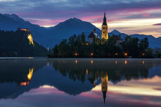 Dramatic sunrise on lake Bled, sunrise view on Bled lake, island, Pilgrimage Church of the Assumption of Maria and Castle with mountain range (Stol, Vrtaca, Begunjscica). Bled, Slovenia,