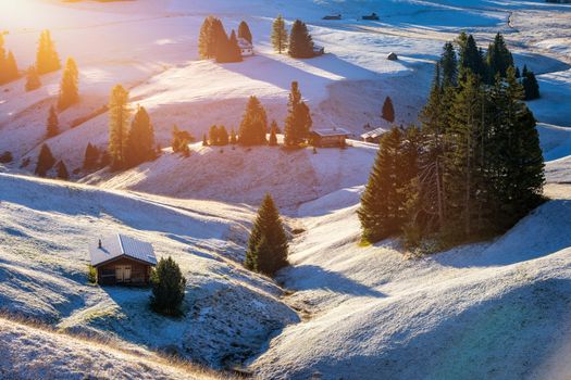 Small wooden farm house, cottage or log cabins on meadow on Alpe di Siusi, Seiser Alm. Alpe di Siusi or Seiser Alm with Sassolungo, Langkofel mountain group, Dolomite Alps, South Tyrol, Italy.