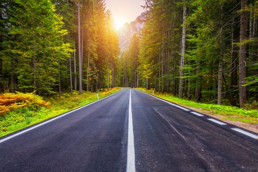 Mountain road. Landscape with rocks, sunny sky with clouds and beautiful asphalt road in the evening in summer. Vintage toning. Travel background. Highway in mountains.  