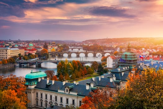 Autumn view to Charles bridge on Vltava river in Prague, Czech Republic. Autumn view to Charles Bridge, Prague old town and Vltava river. Czechia. Scenic autumn view of the Old Town with red foliage.