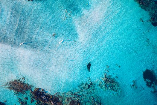 Kayaking in the sea with clear turquoise water. Kayaking, leisure activities on the ocean. Aerial drone bird's eye view of kayak cruising in tropical seascape with turquoise and sapphire clear waters.