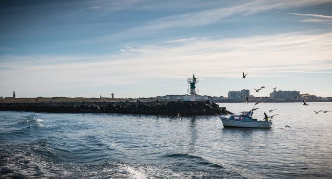 Saint Gilles Croix de Vie, France - September 16, 2018: Small fishing boat entering the harbor accompanied by seagulls on a summer day