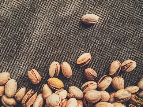 Pistachio nuts on rustic linen background, food and nutrition