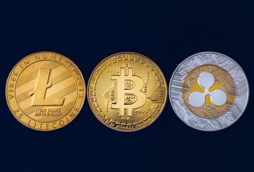 Bitcoin, litecoin and ripple coins currency finance money on graph chart background. Bitcoin as most important cryptocurrency concept. Stack of cryptocurrencies with a golden bitcoin in the middle.