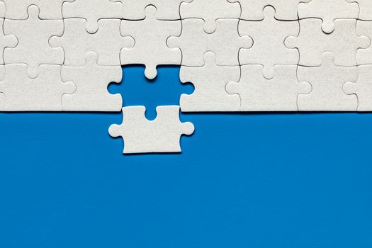 White jigsaw puzzle. White puzzle pieces on color background. Unfinished white jigsaw puzzle pieces on color background. 