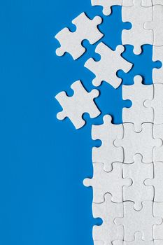 White jigsaw puzzle. White puzzle pieces on color background. Unfinished white jigsaw puzzle pieces on color background. 
