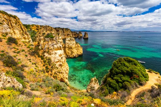 Panoramic view, Ponta da Piedade near Lagos in Algarve, Portugal. Cliff rocks and tourist boat on sea at Ponta da Piedade, Algarve region, Portugal. Ponta da Piedade, Algarve region, Portugal.