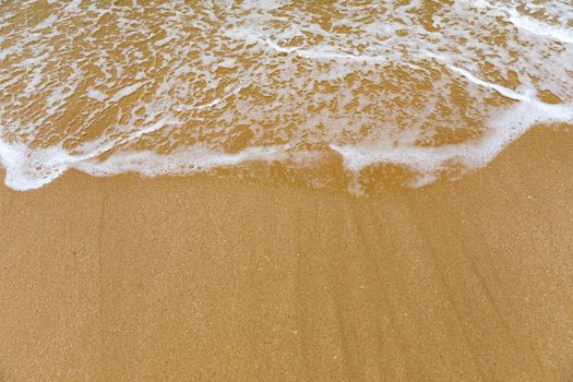Blue ocean wave on sandy beach. Soft wave of blue ocean on sandy beach. Background. Top view of Beautiful beach with tranquil wave, sea and ocean background, summer vacation concept. 