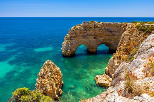 Natural caves at Marinha beach, Algarve Portugal. Rock cliff arches on Marinha beach and turquoise sea water on coast of Portugal in Algarve region. 