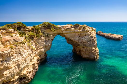 Natural arch above ocean, Arco de Albandeira, Algarve, Portugal. Stone arch at Praia de Albandeira, Lagoa, Algarve, Portugal. View of the natural arch Arco da Albandeira in the Algarve, Portugal. 