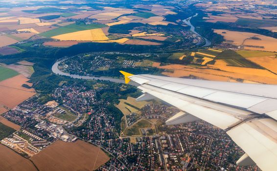 Airplane windows view above the earth on landmark down. View from an airplane window over a wing flying high above farmlands and fields. View from window of plane airplane flying.