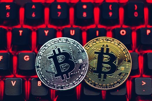 Bitcoin on compuer keyboard in background, symbol of electronic virtual money and mining cryptocurrency concept. Coin crypto currency bitcoin lies on the keyboard. Bitcoin on keyboard.