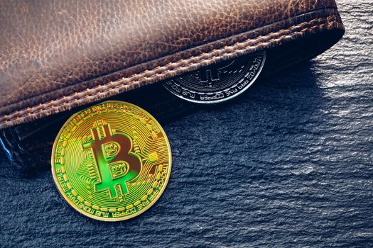 Bitcoin in brown leather wallet. Bitcoin, modern virtual cryptocurrency. Profit from mining crypto currencies. Bitcoin gold coins with wallet, close-up. Virtual cryptocurrency concept.