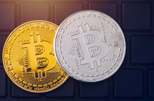 Bitcoin on compuer keyboard in background, symbol of electronic virtual money and mining cryptocurrency concept. Coin crypto currency bitcoin lies on the keyboard. Bitcoin on keyboard.