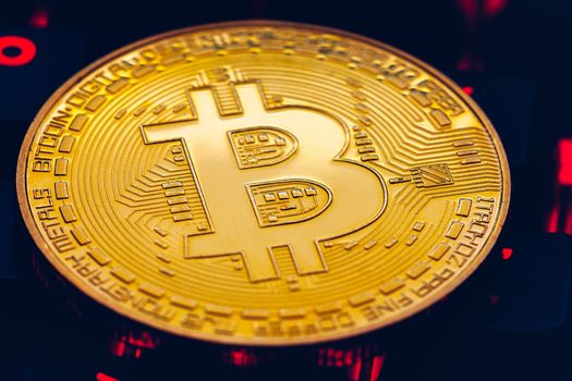 Bitcoin on compuer keyboard in background, symbol of electronic virtual money and mining cryptocurrency concept. Coin crypto currency bitcoin lies on the keyboard. Bitcoin on keyboard.