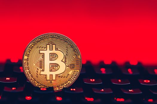 Bitcoin on compuer keyboard in background, symbol of electronic virtual money and mining cryptocurrency concept. Coin crypto currency bitcoin lies on the keyboard. Bitcoin on keyboard.