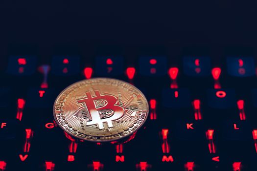 Bitcoin on compuer keyboard in background, symbol of electronic virtual money and mining cryptocurrency concept. Coin crypto currency bitcoin lies on the keyboard. Bitcoin on keyboard.