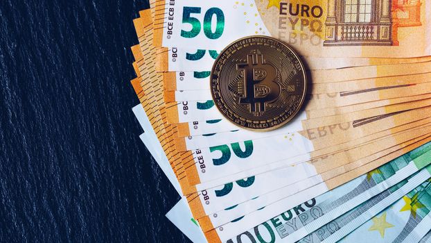 Golden bitcoin over Euro money. Bitcoin cryptocurrency. Crypto currency concept. Bitcoin with euro bills. Bitcoins stacked on euro banknotes.