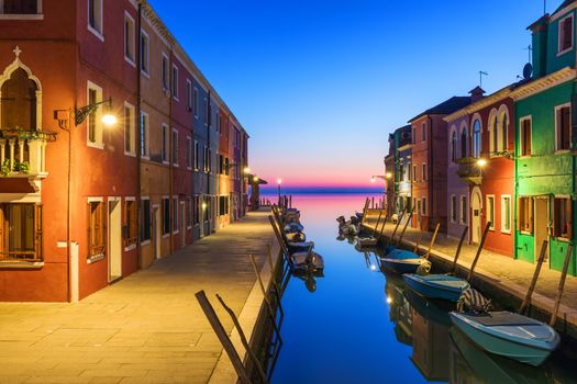 Street view with colorful buildings in Burano island at night, Venice, Italy. Architecture and landmarks of Burano, Venice postcard. Scenic canal and colorful architecture in Burano island near Venice, Italy