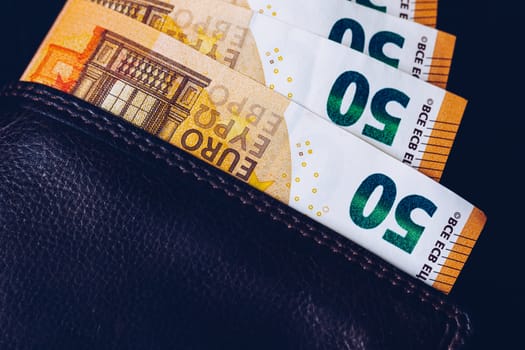 Wallet with Euro banknotes. Cash in the wallet on a black background. Euro money in leather wallet.