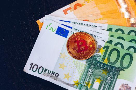 Golden bitcoin over Euro money. Bitcoin cryptocurrency. Crypto currency concept. Bitcoin with euro bills. Bitcoins stacked on euro banknotes.