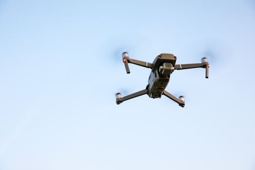 Drone flying over landscape. UAV drone copter flying with digital camera. Drone flying overhead in cloudy blue sky. Quad copter is flying over the  field.