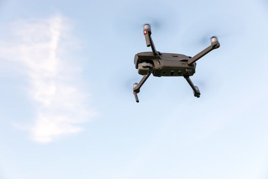 Drone flying over landscape. UAV drone copter flying with digital camera. Drone flying overhead in cloudy blue sky. Quad copter is flying over the  field.