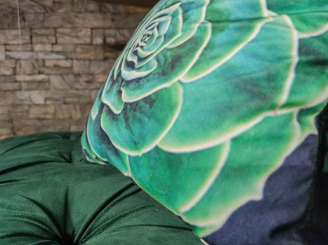 a mulicolor pillow on a green sofa