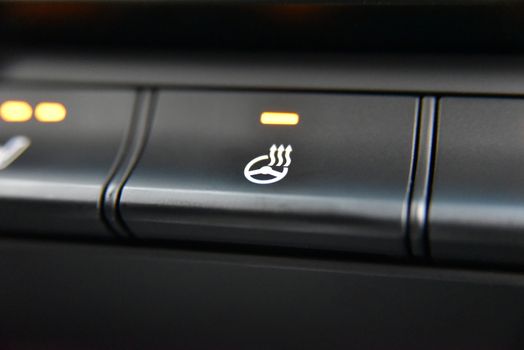 the control panel of a modern car with a button for heating the steering wheel