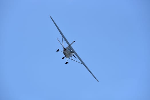 A small single engine aircraft flying in the blue sky