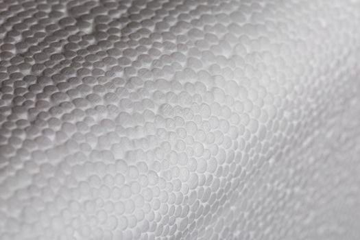 Simple close-up bumpy background of white polystyrene foam or styrofoam, white on white backdrop with selective focus.