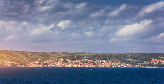 Supetar city in Brac island, Croatia. View from the sea. Picturesque scenic view on Supetar on Brac island, Croatia. Panoramic view on harbor of town Supetar from the side of sea. Brac, Croatia.
