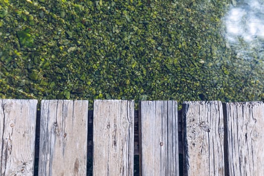 Wooden board empty over sea, can be used for display or present a product. Summer season. Empty perspective wooden planks over the reflection of green water, product display template.
