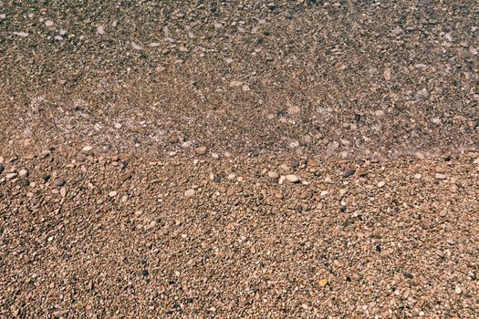 Stones under water. Sea pebbles on the beach. Sea pebbles on the beach sand with transparent water. Natural sea stones closeup. Beach smooth pebbles. Tourism and travel themed. Vacation background. 