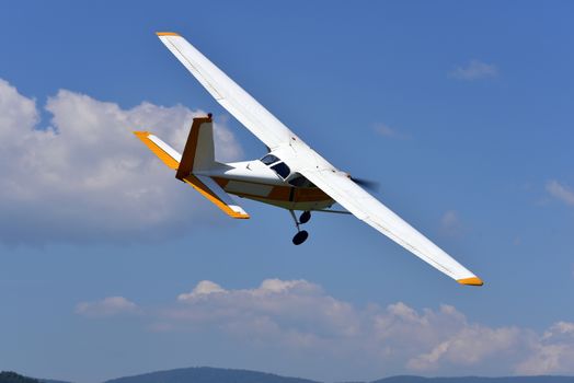 A small single engine aircraft flying in the blue sky