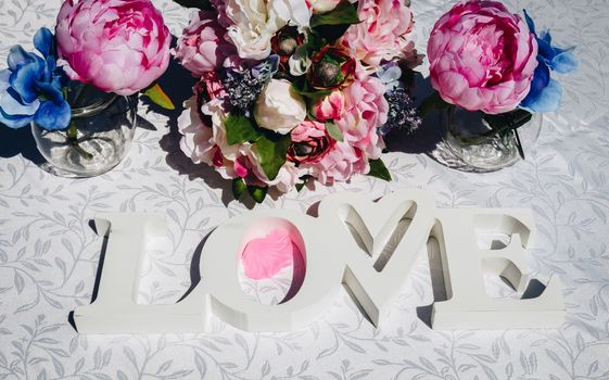 Creative layout with colorful flowers, leaves and Word LOVE. Love concept.