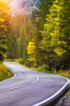 Mountain road. Landscape with rocks, sunny sky with clouds and beautiful asphalt road in the evening in summer. Vintage toning. Travel background. Highway in mountains.  