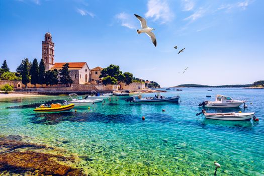 View at amazing archipelago with fishing boats in front of town Hvar, Croatia. Harbor of old Adriatic island town Hvar with seagull's flying over the city. Amazing Hvar city on Hvar island, Croatia. 