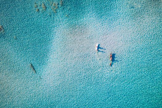 Kayaking in the sea with clear turquoise water. Kayaking, leisure activities on the ocean. Aerial drone bird's eye view of kayak cruising in tropical seascape with turquoise and sapphire clear waters.