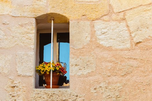 stone wall with an old window and a yellow flower pot