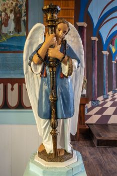 Kalapana, Hawaii, USA. - January 14, 2020: Mary, Star of the Sea Catholic Church. Closeup on one of two similar angel statues standing on both sides of altar. Blue wall and brown beam in back. part of paintings.