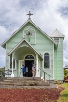 Kalapana, Hawaii, USA. - January 14, 2020: Mary, Star of the Sea Catholic Church. Portrait of entrance under white cloudscape shows pale green painted wooden building with double cross. People present.