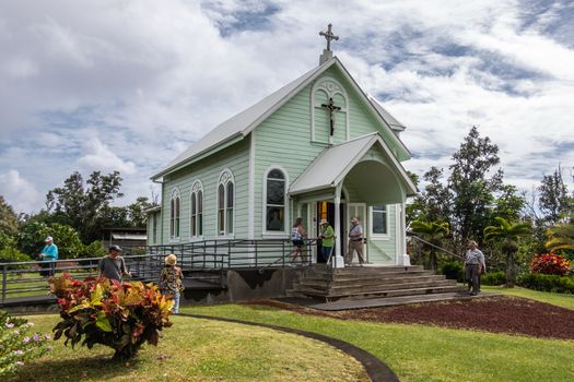 Kalapana, Hawaii, USA. - January 14, 2020: Mary, Star of the Sea light green wooden Catholic Church in its green garden under white cloudscape with blue patches. People present.