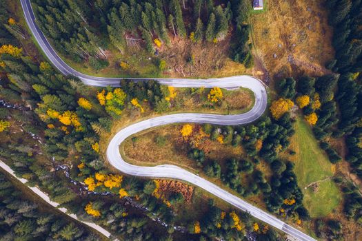 Curved bending road in the forest. Aerial image of a road. Forrest pattern. Scenic curvy road seen from a drone in autumn. Aerial top down view of zig zag winding mountain road, drone shot.
