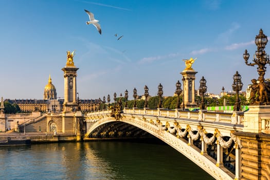 Pont Alexandre III bridge over river Seine in the sunny summer morning. Bridge decorated with ornate Art Nouveau lamps and sculptures. The Alexander III Bridge across Seine river in Paris, France.