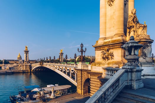 Pont Alexandre III bridge over river Seine in the sunny summer morning. Bridge decorated with ornate Art Nouveau lamps and sculptures. The Alexander III Bridge across Seine river in Paris, France.