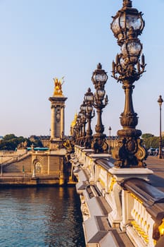 Pont Alexandre III bridge over river Seine in the sunny summer morning. Bridge decorated with ornate Art Nouveau lamps and sculptures. The Alexander III Bridge across Seine river in Paris, France.