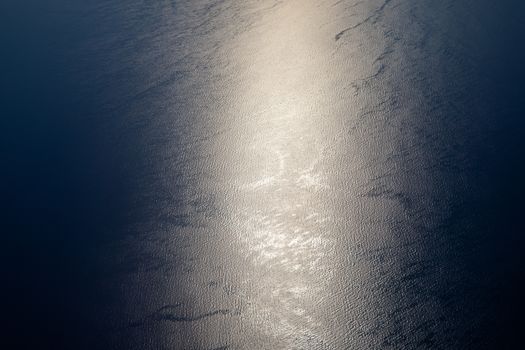 Sunlight twinkling and reflecting off sea water. Sparkles on water. Sun reflecting on the ocean surface, view from the plane, concept of travel. 