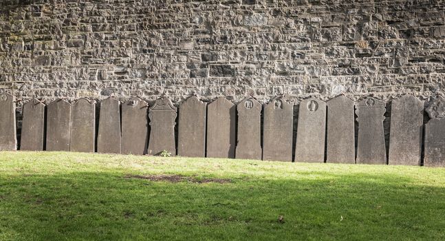 Dublin, Ireland - February 13, 2019: Tombstones laid against a wall in the cemetery at Arbor Hill next to the Church of the Sacred Heart on a winter day