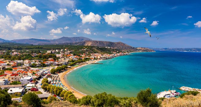 Greek holidays, beautiful Kalyves village with turquoise sea in Crete island, Greece. View of Kalyves beach, Crete. Seagulls flying over the beach in Kalyves, Crete, Greece
